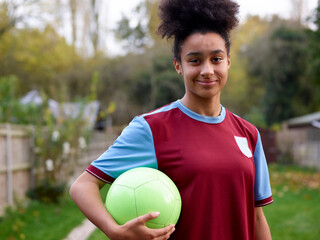Portrait of female soccer player with ball outdoors