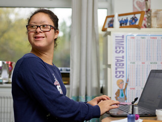 Girl with Down Syndrome using laptop at home
