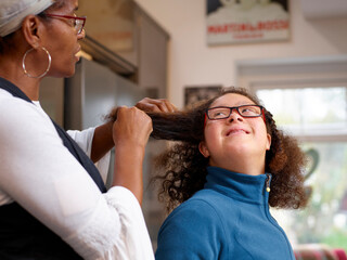 Mother doing hair of daughter with Down Syndrome - obrazy, fototapety, plakaty