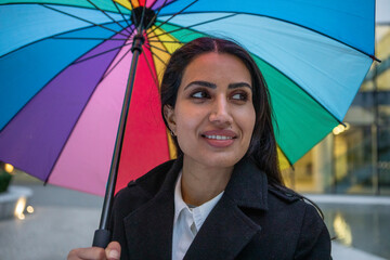 UK, London, Smiling woman holding colorful umbrella in city