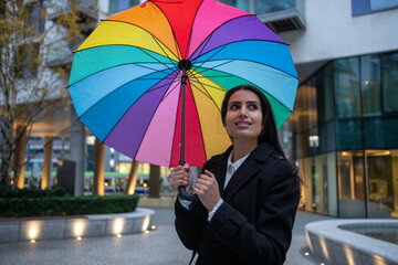 UK, London, Smiling woman holding colorful umbrella in city