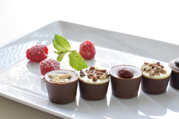 Assorted Chocolates and Raspberries on White Dish.