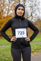 Portrait of woman in black sports clothing and hijab with race number