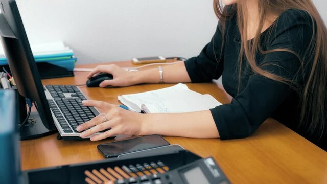 Employee working on computer in office. Scrolling through a spreadsheets. Office worker during work. Side view of hand scrolling the wheel of a computer mouse.