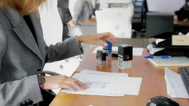 Office worker signing and stamping documents. Preparation of documents for the client. Documentation, reporting, bookkeeping, workflow