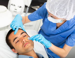 Young man receiving innovative anti-aging carboxytherapy procedure for facial skin in aesthetic...