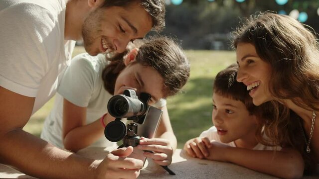 A happy family is excited at the park while the daughter looks through a monocular telescope.