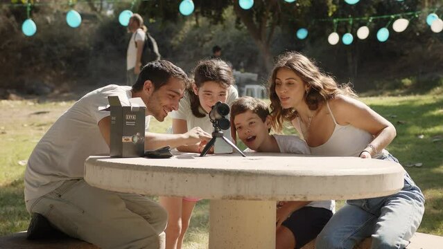 A happy family enjoying their monocular telescope at the park. Static shot