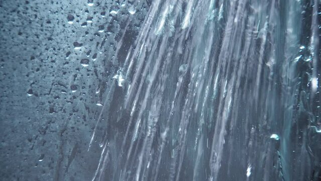 Water being sprayed on shower glass surface. Abstract background. 