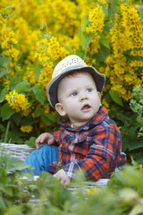 Smiling child plays in flowers. Baby in blooming spring garden. Summertime scene from childhood