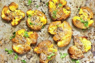 smashed potato, on parchment paper just out of the oven. smashed potatoes.  top view