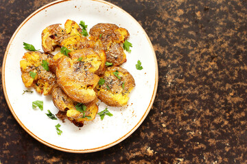 crushed potatoes. smashed potatoes. recipes for Australian cuisine. the potatoes are boiled in a shell, broken and baked in an oven with spices. top view