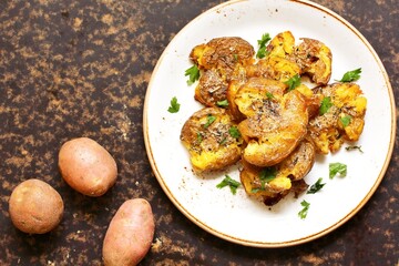 crushed potatoes. smashed potatoes. recipes for Australian cuisine. the potatoes are boiled in a shell, broken and baked in an oven with spices. top view