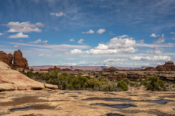 Potholes Filled With Water Dot The Cliff Edge Looking Toward The La Sal Mountains