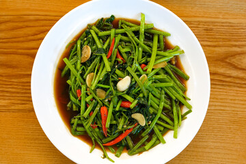 Fried morning glory with chili on wooden table.