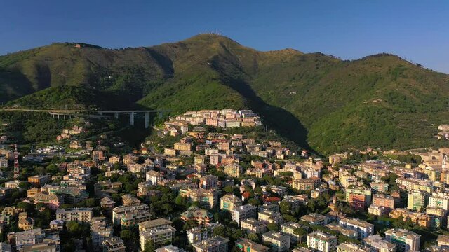 Aerial view overlooking the cityscape of east Genova, golden hour in Italy - descending, drone shot