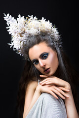 Beautiful woman with creative fantasy makeup as Snow Queen or Ice Fairy isolated on black background.	