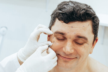 Cosmetologist conducts rejuvenation procedure puts Botox injection on man. The concept rejuvenating...