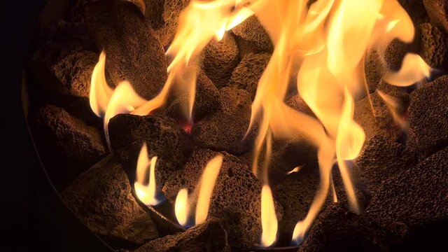 Flames and lava rocks from a propone portable fire pit.