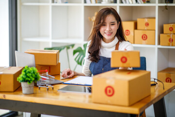 Startup SME small business entrepreneur SME or freelance Asian woman using a laptop with box, Young success Asian woman with her hand lift up, online marketing packaging box and delivery, SME concept.