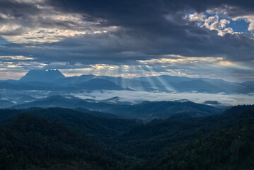 Obraz premium Light ray over blue mountain range silhouette with blue sky cloud in a morning