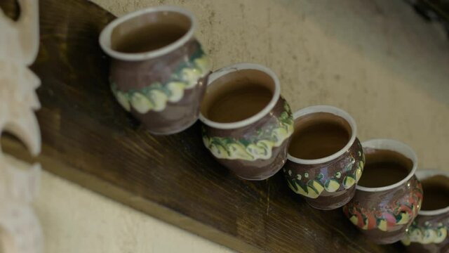 Close Up Of Ceramic Clay Tea Cups Hanging On The Wall. low angle, slider shot