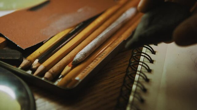 Fixing drawing with kneaded eraser or rubber, sketchbook, hand and pile of pencils closeup