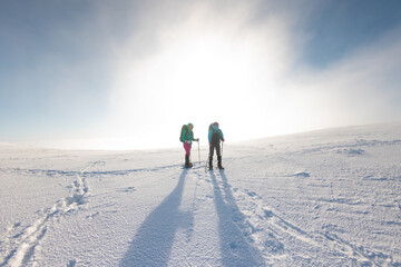Fototapeta na wymiar Two women walk in snowshoes in the snow