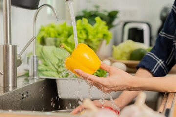 Close up hand of asian young housekeeper woman, washing sweet pepper, yellow paprika, vegetables...
