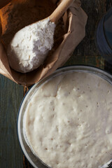 Wheat flour starter culture is ready to be added to the dough. Spoon with flour and water on the table. Top view.