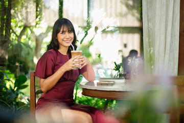 Portrait of young Indian female in coffee shop with relax environment Tanned skin Asian woman purple