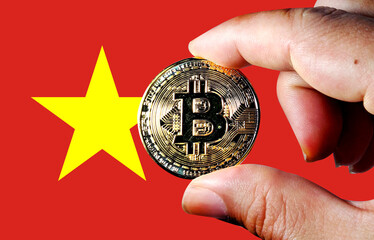 Hold a physical version of Bitcoin (the new virtual currency) and the flag of Vietnam. Vietnam...