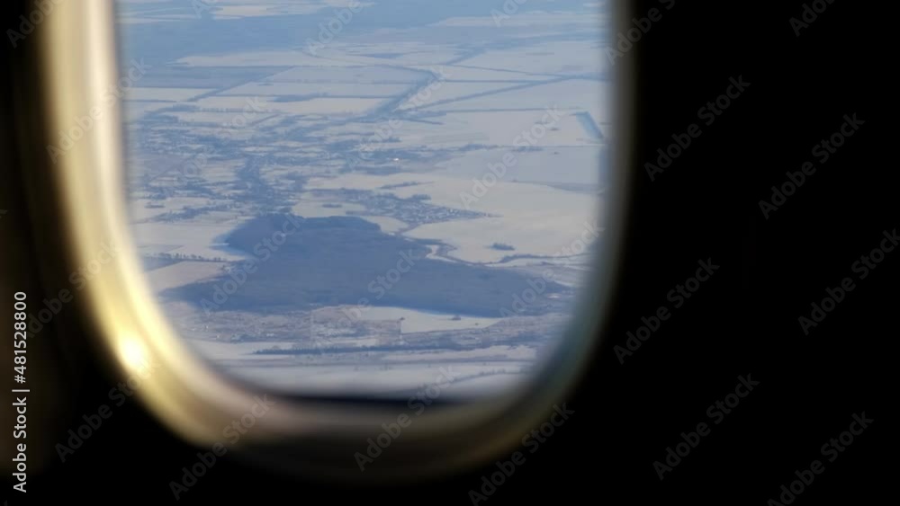 Poster the view from the plane window of the fields covered with snow on a winter day.