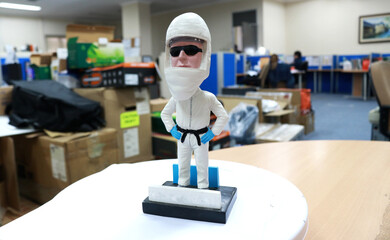 Photo of a toy like a white statue, this cute toy wears glasses, a helmet and a karate suit