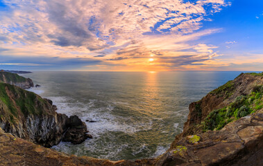Coastal cliffs and silky ocean by Devil's Slide trail in California at sunset