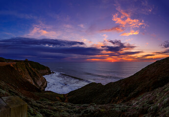 Naklejka na ściany i meble Coastal cliffs and silky ocean by Devil's Slide trail in California at sunset