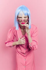 portrait of a woman in sunglasses wears a blue wig makeup pink background
