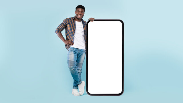 Casual black man leaning on big white empty smartphone screen