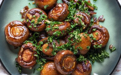 Plate of fried mushrooms with dill, garlic, pine nuts and parsley on the wooden table