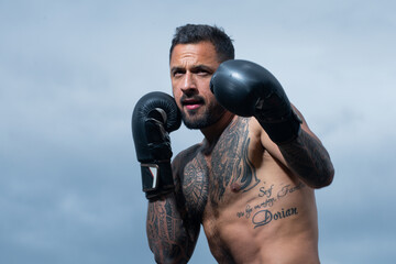 Boxer fighter training outdoors. Sportsman muay thai boxer fighting in gloves. Sporty man during...