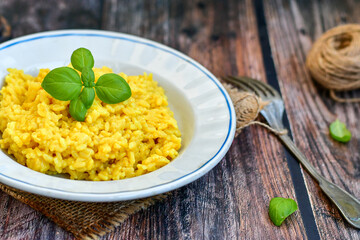  Italian  creamy risotto milanese  with parmesan cheese and fresh basil on rustic background