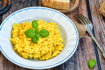  Italian  creamy risotto milanese  with parmesan cheese and fresh basil on rustic background