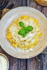  Italian  home made  creamy risotto milanese  with parmesan cheese and fresh basil on rustic background