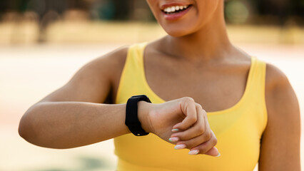 Sporty African woman checking fitness tracker during workout break