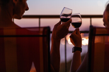 Silhouette of couple drinking wine at the sea view terrace in the evening. Valentine day image. - Powered by Adobe