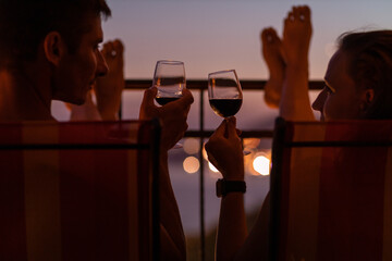Romantic couple talking and have wine at sea view terrace at sunset. Valentine day image.
