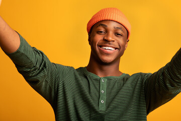Self-Portrait. Cheerful African American Guy Taking Selfie Over Yellow Background