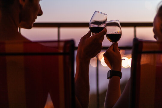 Silhouette of couple drinking wine at the sea view terrace in the evening. Valentine day image.