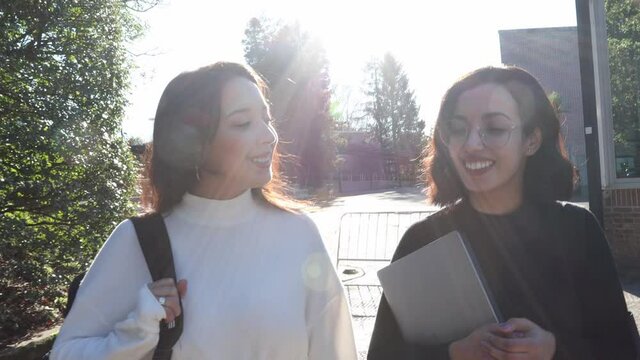 Two college students going for their class while talking and having chit chat fun. Laugh and love friendship concept. Return and begin a career, grade or study. African berber girls studying