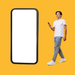 Young bearded man walking with cellphone isolated on yellow wall